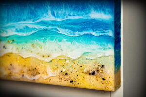 Close up of details of rocks, sand, gold flakes, and a deep aquamarine sea in piece #2